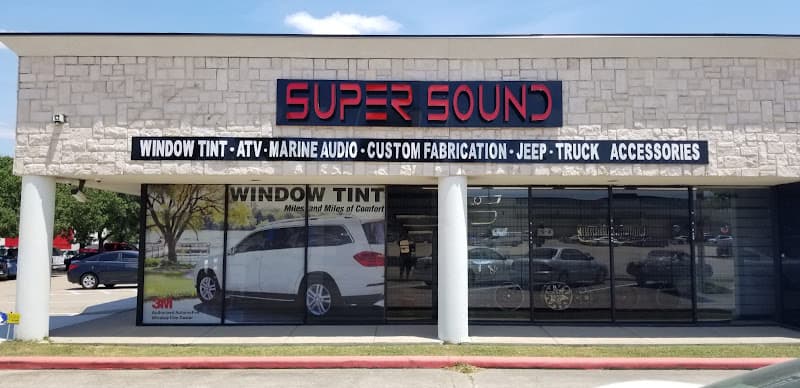 Stone storefront with red sign and window tint banner at Super Sound and Security in Rockwall, Texas
