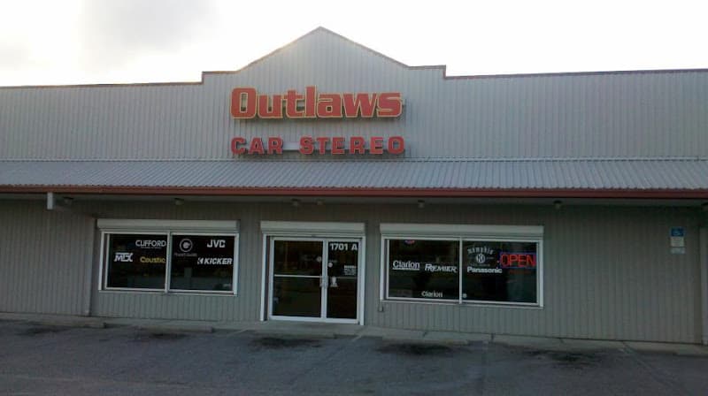 Storefront with red sign and logo decals in windows at Outlaws Car Stereo in Pensacola, Florida