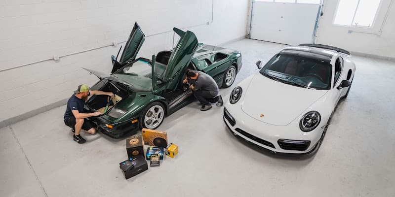 Overhead view of two men working on a green sports car in a garage at Blue Chip Car Audio in Englewood, Colorado