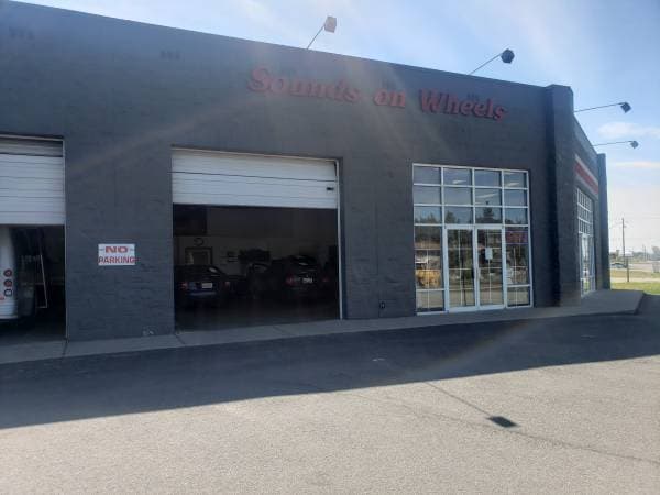 Gray building with two open service bays and a red sign at Sounds On Wheels in Spokane Valley, Washington