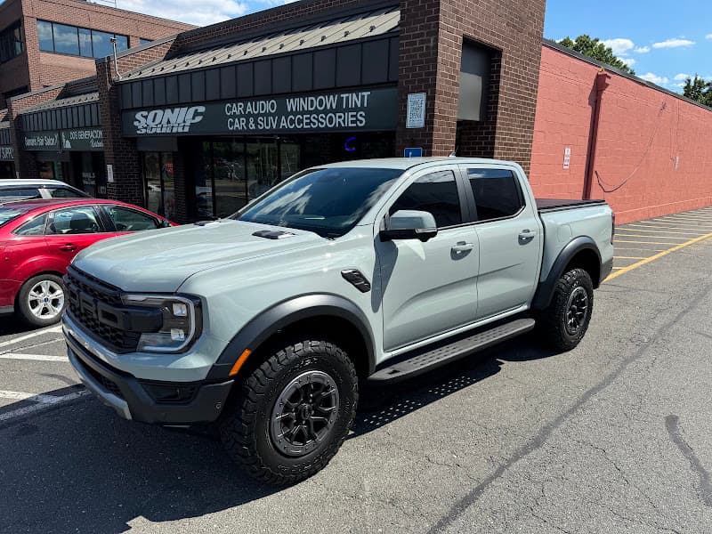 Gray pickup truck with off-road tires parked outside a storefront at Sonic Sound in Arlington, Virginia