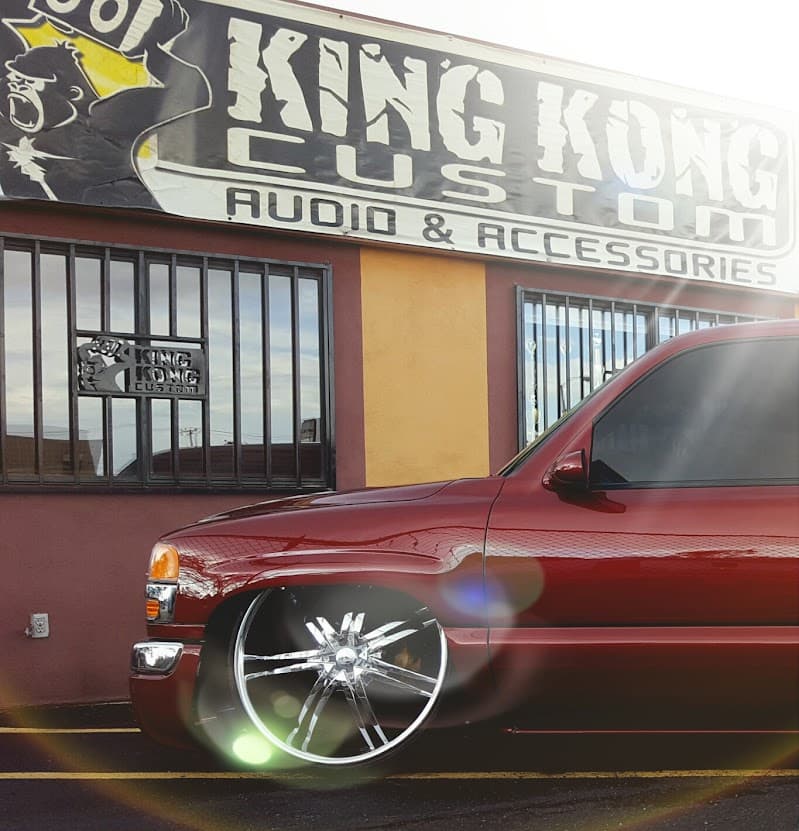 Red pickup truck with chrome wheels parked outside a shop sign at KING KONG CUSTOMS in Albuquerque, New Mexico