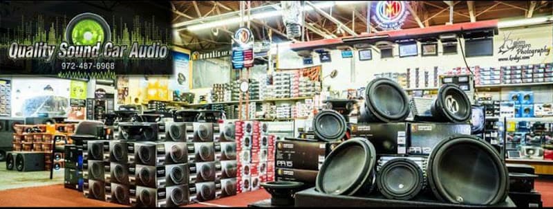 Showroom shelves stacked with subwoofers and speakers at Quality Sound Car Audio in Garland, Texas