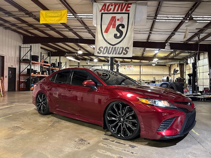 Red sedan with black wheels parked in a shop bay at Active Sounds Customs in Kernersville, North Carolina