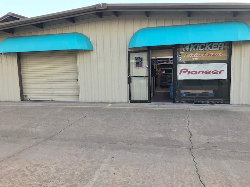 Storefront with teal awnings and Kicker and Pioneer signs at Kustom Kar Stereo in Houston, Texas
