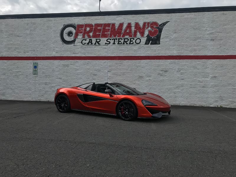 Orange sports car parked in front of a white block wall at Freeman's Car Stereo in Charlotte, North Carolina