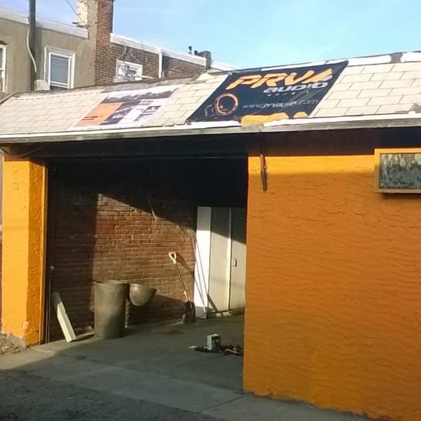 Orange-walled garage with PRV Audio banner sign at C T Custom car audio and security in Philadelphia, Pennsylvania