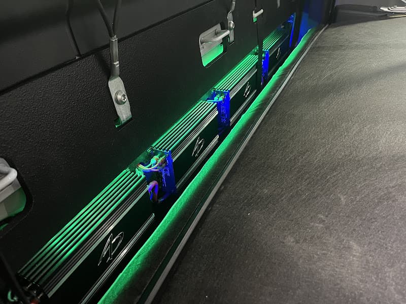 Amplifiers mounted on a black panel with green lighting at Audio Evolutions OCF in Lake Wales, Florida