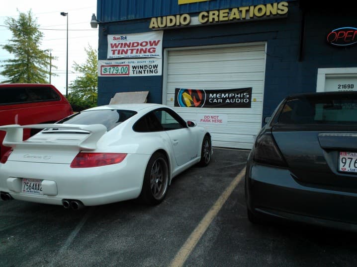 White sports coupe parked outside a shop with window tinting signs at Audio Creations By Tint'em in Pelham, Alabama