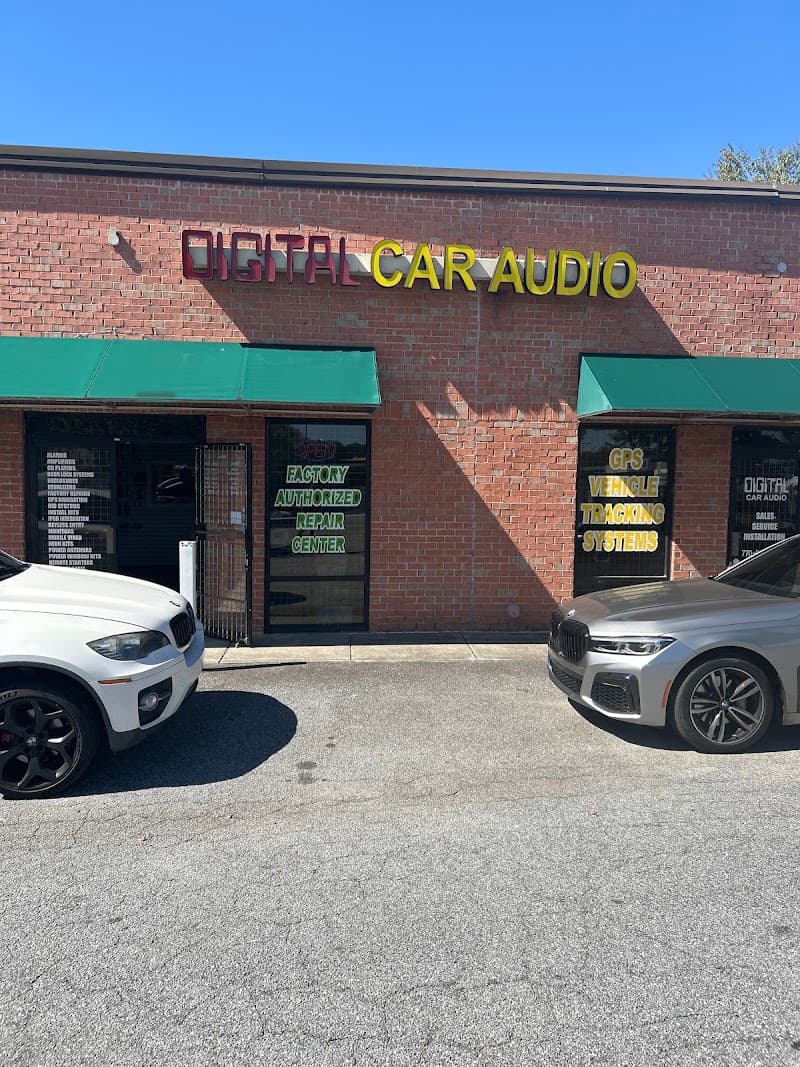 Brick storefront with green awnings and two parked cars at Digital Car Audio in Lawrenceville, Georgia
